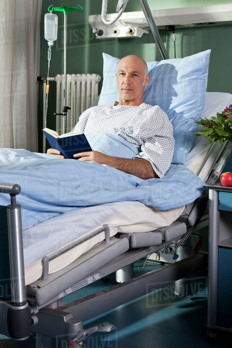 Portrait of a man sitting with a book in a hospital bed Royalty-free stock photo